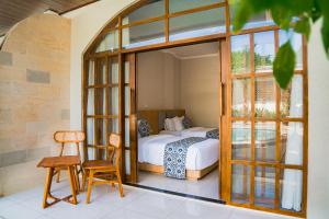 a bedroom with a bed and a table and a chair at Sandat Mas Uluwatu in Uluwatu +21 photos