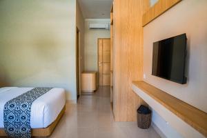a bedroom with a bed and a flat screen tv at Sandat Mas Uluwatu in Uluwatu