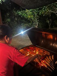 a man is cooking hot dogs on a grill at Pepper Trails Riverstone in Polwattekanda