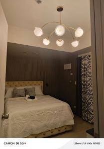 a bedroom with a bed with a chandelier above it at Davao city One Lakeshore Drive at the back of sm lanang in Davao City +17 photos