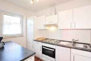 a kitchen with white cabinets and a sink at Haushaelfte-Kuddel-104 in Böhl