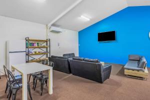 a living room with black leather furniture and a blue wall at Reflections Coffs Harbour - Holiday Park in Coffs Harbour