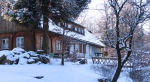 uma casa com neve no chão em frente dela em Pokoje Gościnne Arnika Górska em Szklarska Poręba