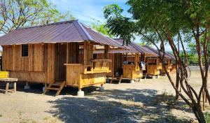 a row of wooden huts sitting next to trees at Beachfront Aircon Kubo for 4pax in Caba +3 photos