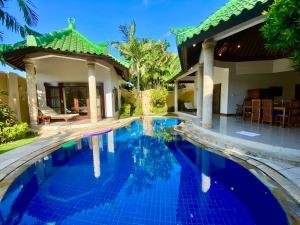 a swimming pool in front of a house at Bali Emerald Villas in Sanur