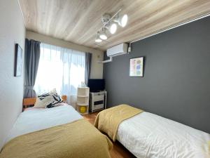 a bedroom with two beds and a window at サイプレス平岸 in Sapporo