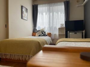 a hotel room with two beds and a window at サイプレス平岸 in Sapporo