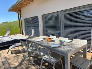 a wooden table and chairs on a deck with a table and chairsktop at Maison chez Louis in Asuel