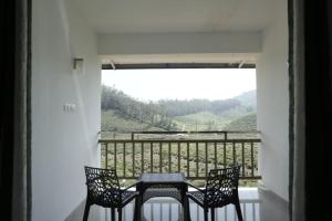 a table and two chairs on a balcony with a view at Vagamon Hill Resort in Vagamon