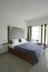 a bedroom with a large bed with a large window at Vagamon Hill Resort in Vagamon