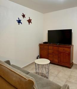 a living room with a couch and a flat screen tv at Le Coeur des Iles in Sainte-Anne