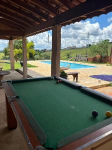 a pool table in front of a swimming pool at Recanto do Batata in Atibaia