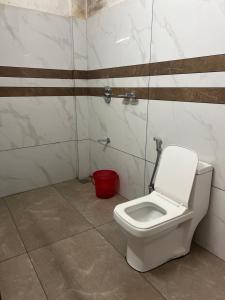 a bathroom with a white toilet and a red bucket at morriz inn in Kalpetta