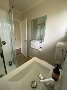a white bathroom with a sink and a shower at Rehutai Beach House in Paihia +12 photos