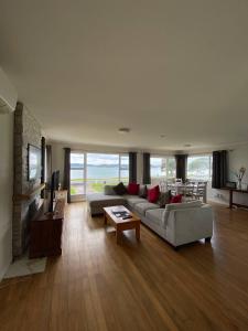 a large living room with a couch and a tv at Rehutai Beach House in Paihia