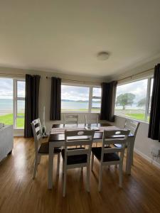 a dining room with a table and chairs and windows at Rehutai Beach House in Paihia