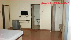 a bedroom with a bed and a tv and a mirror at Hotel Shiv Sai in Shirdi