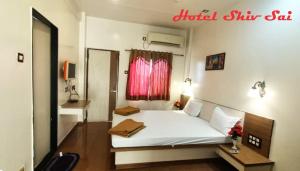 a bedroom with a white bed and a red window at Hotel Shiv Sai in Shirdi