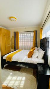a bedroom with a large bed with yellow curtains at Godly Homes in Ruiru