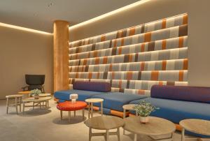 a lobby with a blue couch and tables and chairs at Go Hotel Khon Kaen Campas in Ban Nong Waeng