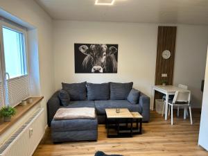 a living room with a blue couch and a cow picture at bei gitta in Olpe