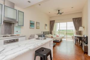 a kitchen with a counter and a living room at Straits Quay Waterside Penang in Tanjong Tokong