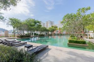 a swimming pool with lounge chairs and trees at Straits Quay Waterside Penang in Tanjong Tokong