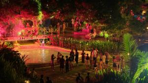 a group of people standing around a pond at night at JungleNest Resort in General Luna +50 photos