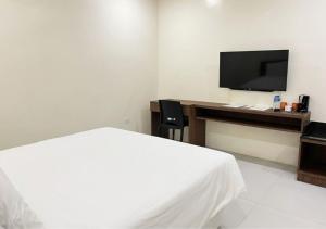 a bedroom with a bed and a desk with a television at Cris Inn - Bayugan in Bayugan City