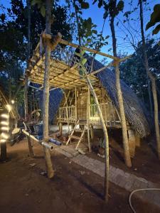a bamboo house with a thatched roof at night at v kudil in Auroville