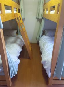 two bunk beds in a room with white sheets at 黒潮の家 ドミトリー in Kuroshio