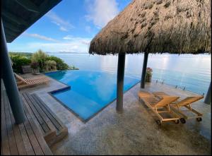 a swimming pool with two chairs and a straw umbrella at Raitotoka Eco Resort in Matei