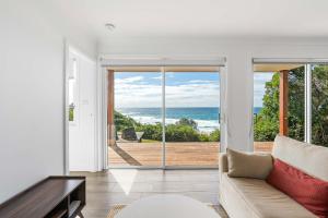 a living room with a couch and a view of the ocean at Waters Edge - beachside home near Rennies Beach in Ulladulla