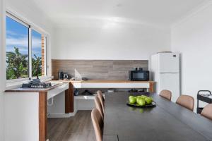 a kitchen with a table with a plate of fruit on it at Waters Edge - beachside home near Rennies Beach in Ulladulla