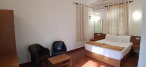 a bedroom with a bed and a desk and two chairs at SUSAGADE in Vagator