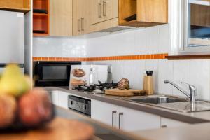a kitchen with a sink and a stove top oven at Ma Te Kokorou - pet-friendly Huskisson pool escape in Huskisson