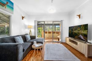 a living room with a couch and a flat screen tv at Ma Te Kokorou - pet-friendly Huskisson pool escape in Huskisson