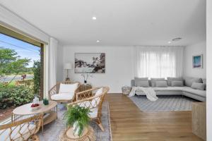a living room with a couch and a table at Collingwood - 4BR modern beachfront holiday home in Vincentia