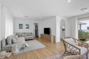 a living room with a couch and a tv at Collingwood - 4BR modern beachfront holiday home in Vincentia