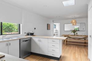 a kitchen with white cabinets and a wooden floor at Collingwood - 4BR modern beachfront holiday home in Vincentia