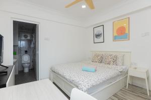 a white bedroom with a bed and a bathroom at Eastern Apartment in Jelutong