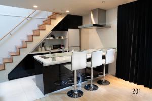 a kitchen with a counter with white chairs and a staircase at Shibuya City House 渋谷シティハウス in Tokyo