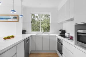 a white kitchen with a sink and a window at Fathoms 13 Mollymook Beach in Mollymook