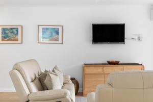 a living room with a chair and a tv at Fathoms 13 Mollymook Beach in Mollymook