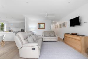 a living room with two white chairs and a tv at Fathoms 13 Mollymook Beach in Mollymook +29 photos