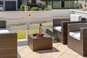 a patio with wicker chairs and a table with a bottle of wine at Oceans 13 in Manyana