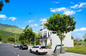 a white building with cars parked on the side of a road at COBI’s Home in Cam Lâm +66 photos