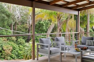 a screened porch with chairs and tables and trees at Simmons Sanctuary Ulladulla in Ulladulla
