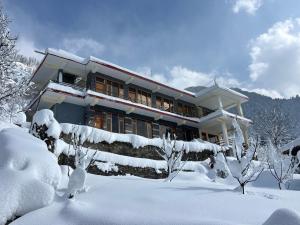 a house covered in snow with snow covered trees at Jumanji homestay in Nagar