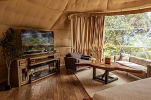 a living room with a tv and a couch and a table at Tropical Escape Domes in Guápiles